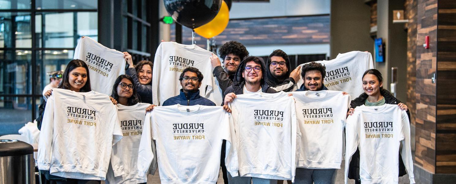 Students hold up PFW sweatshirts.