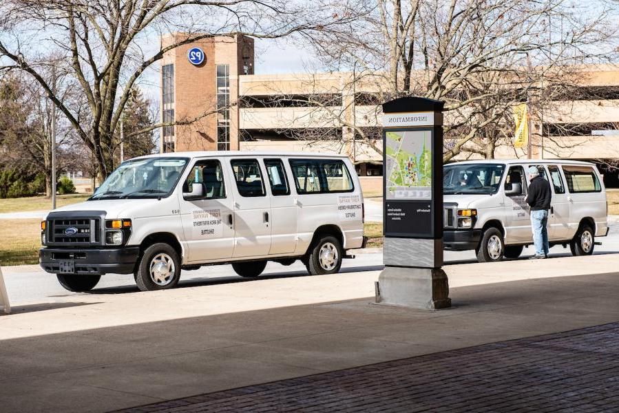 Two student shuttle vans waiting on students.